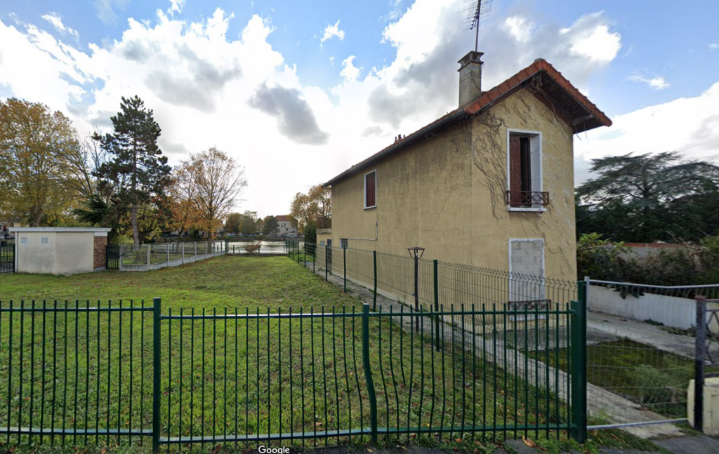 Photographie de la parcelle cadastrée n°3824 à Livry-Gargan en 2020, montrant un bâtiment avant sa démolition et l'aménagement du terrain, avec le Lac de Sévigné visible en arrière-plan.