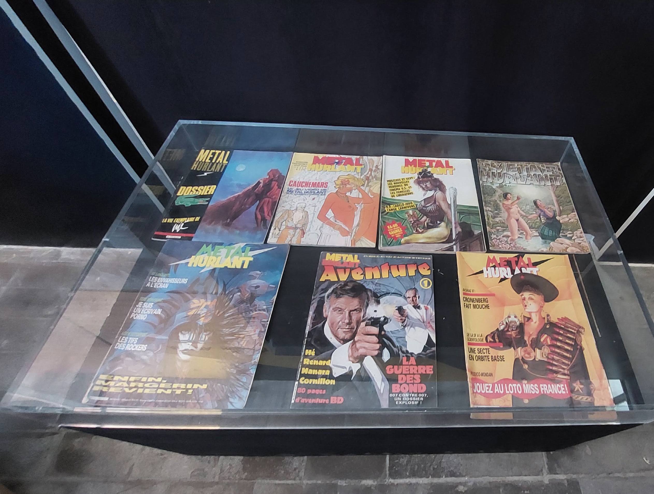 Vitrine d'exposition présentant une sélection de couvertures de Métal Hurlant et Métal Aventure des années 1970 et 1980, photographiée au RDVBD Amiens 2025.